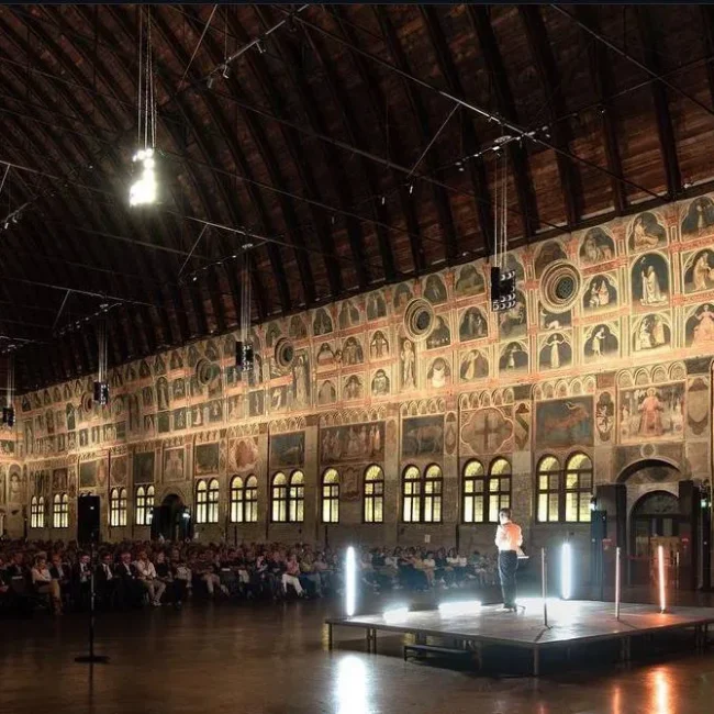 Manifestazioni - Salone con palco e molte persone a sedere ad ascoltare